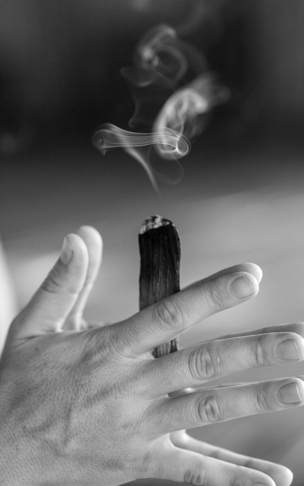 Close up photo sequence showing cigarette smoke curling up from between fingers in artful black and white.