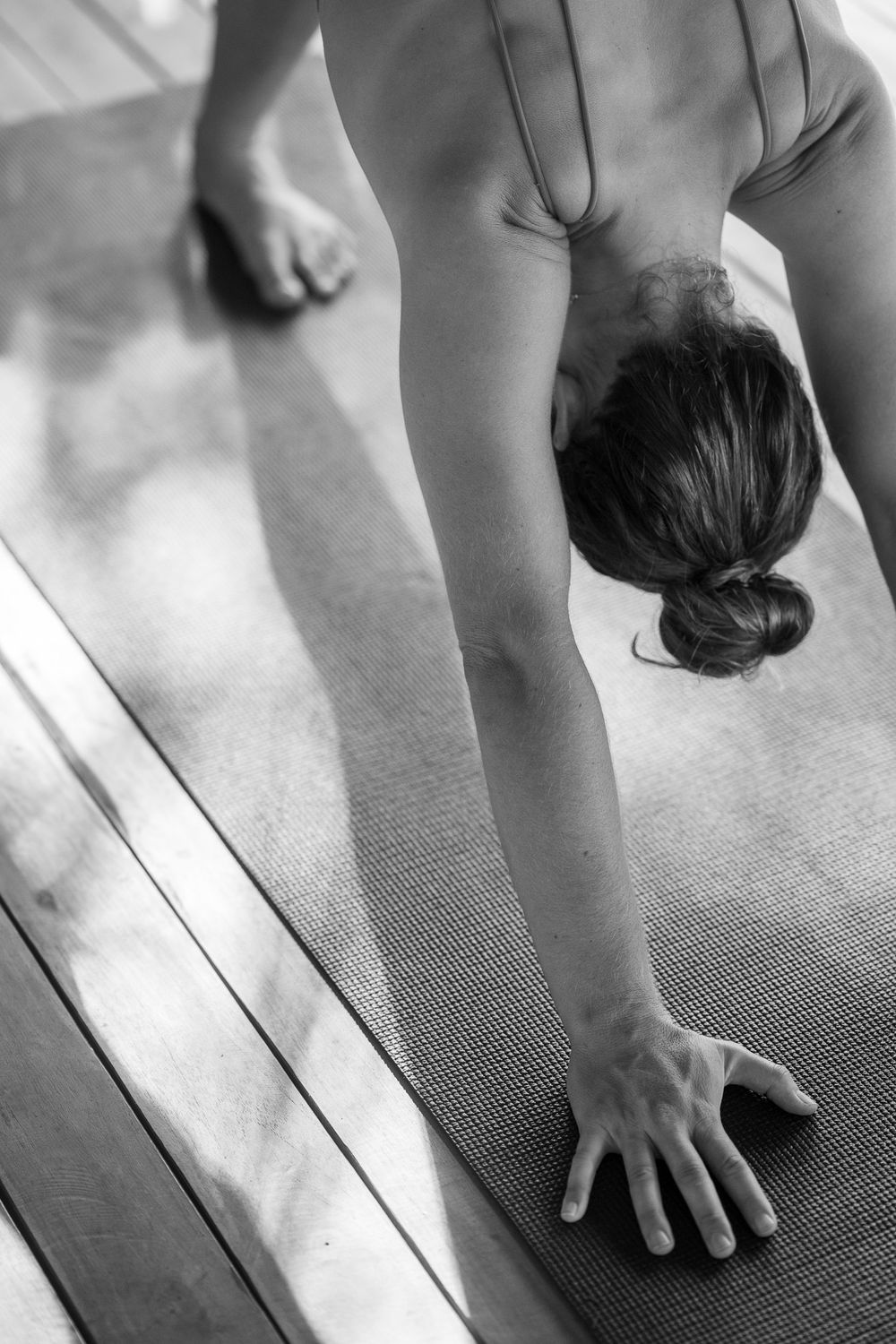 Close-up progression of hands and feet positioning during a yoga pose on a black mat.
