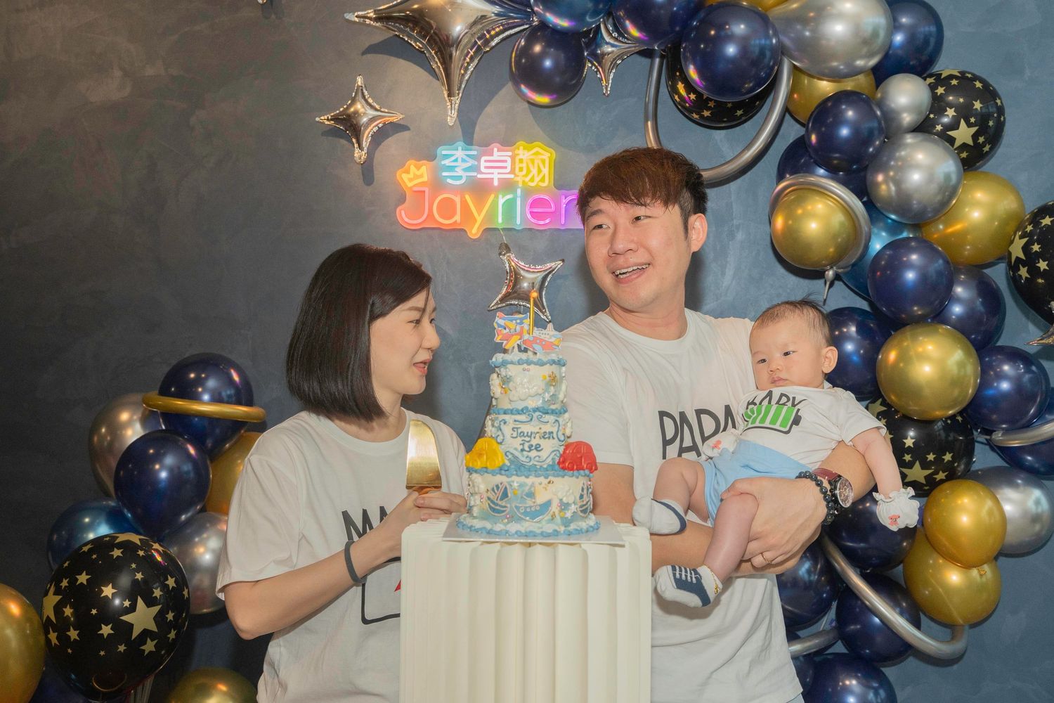 Birthday celebration with cake, presents and blue and gold balloon arch decorations at festive party setting.