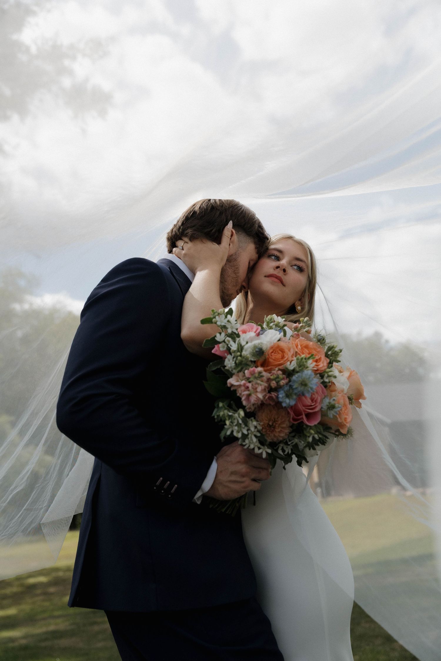 Newlyweds lean over their tiered wedding cake during cake cutting ceremony.