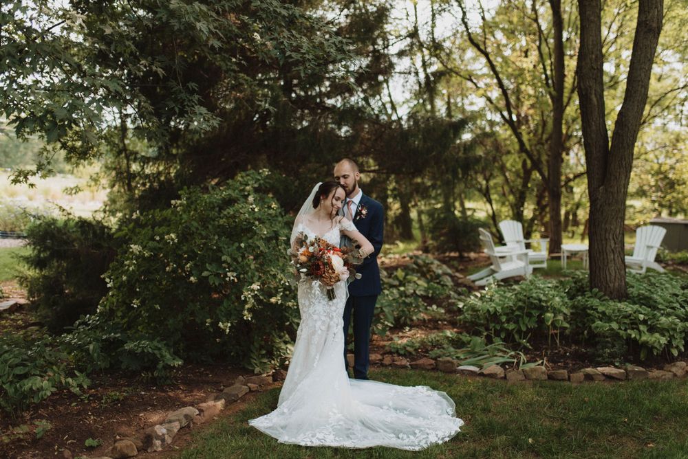A couple stands together in a lush garden setting during their wedding ceremony on a sunny afternoon.