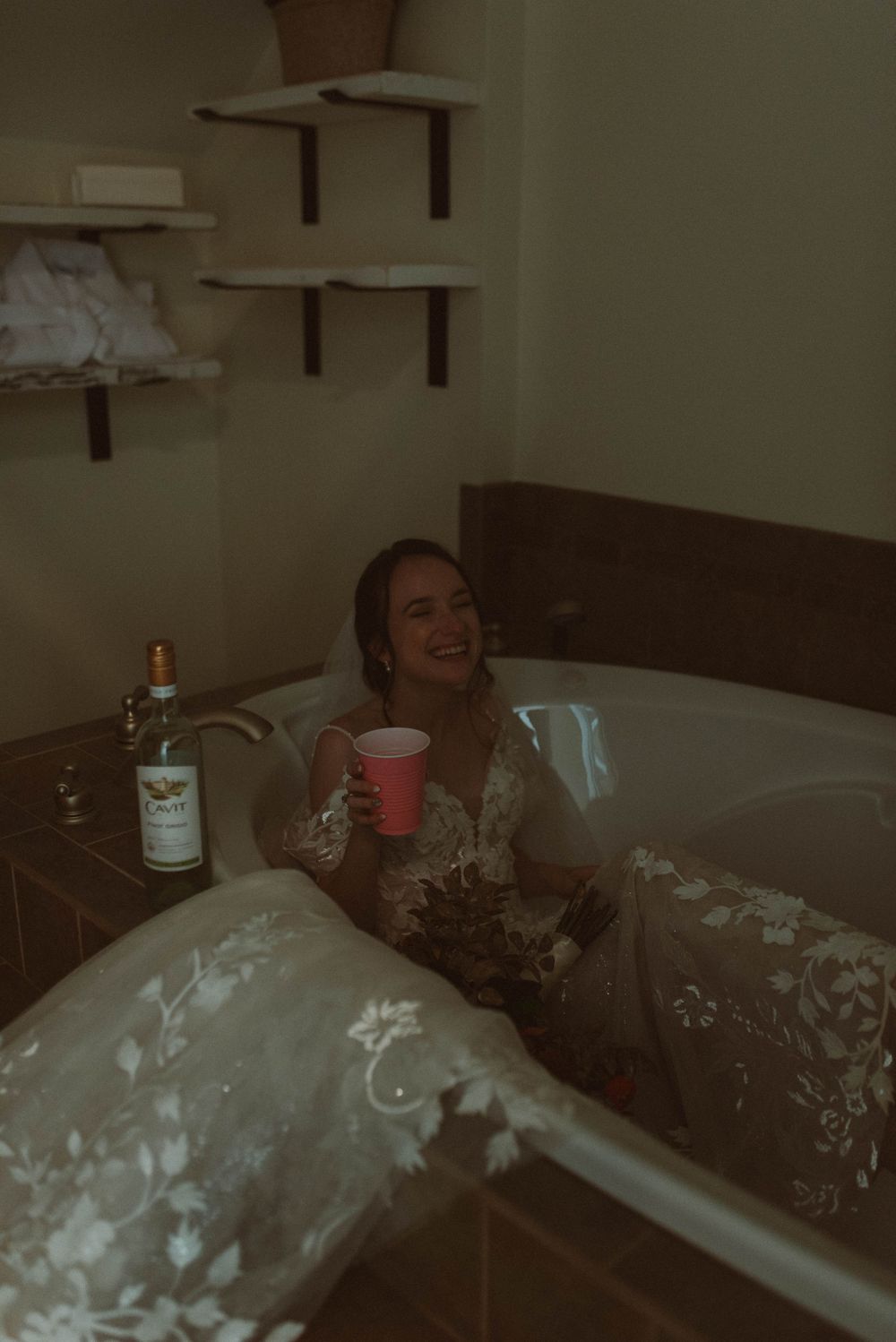 Someone relaxes in a bathtub while holding a red cup with a bottle of Grey Goose vodka nearby.