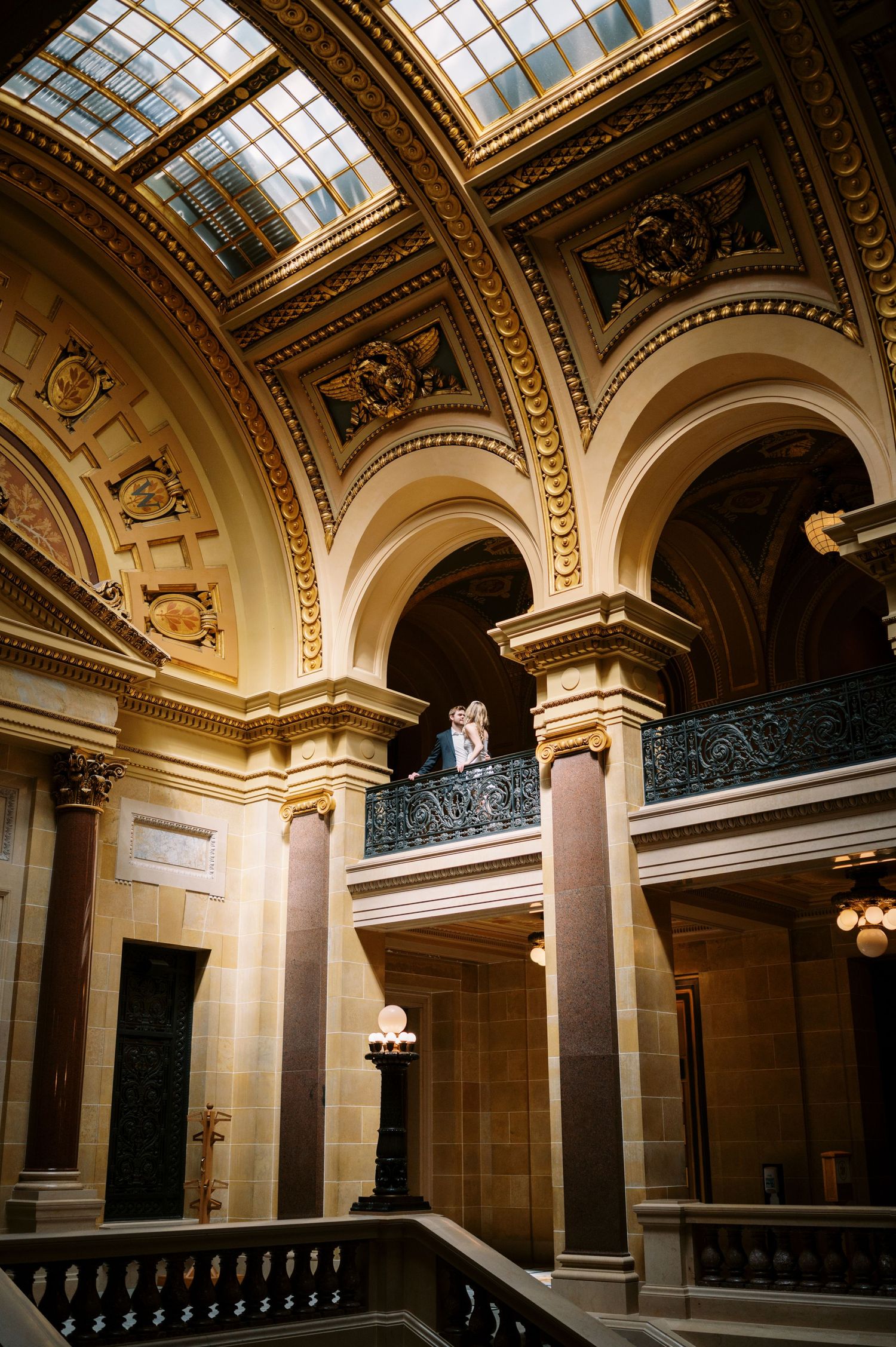 Elegant interior architecture featuring ornate arches, columns and skylights in a grand historic building hallway.