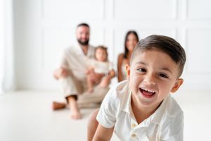 Family members laughing and having fun together in bright white room with joyful expressions.