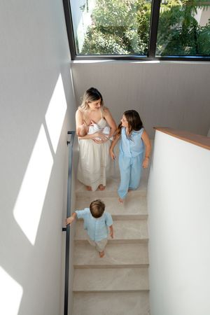 Tender couple sits together on modern white staircase in sunlit room, creating intimate minimalist portrait.