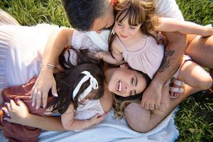 Family group lying together and sharing joyful moment in green grass on sunny day.