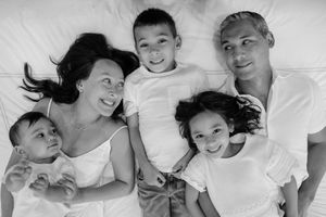 A black and white photo collage shows tender family moments of parents and children laying together on white bedding.