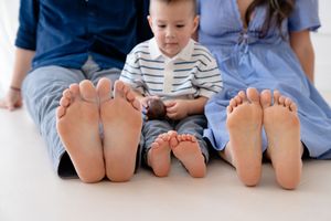 Row of bare feet lined up in a casual family photo showing multiple generations sitting together.