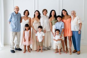 Multi-generation family members gathered wearing coordinated beige and coral outfits for a group photo session.
