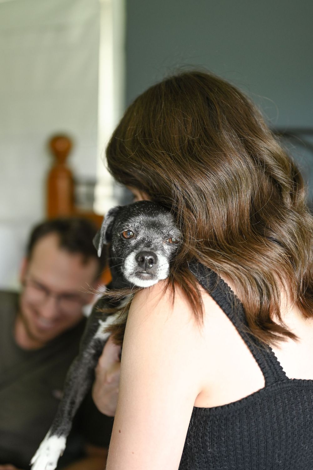 Close-up shots of someone with a black and white dog resting their heads together.
