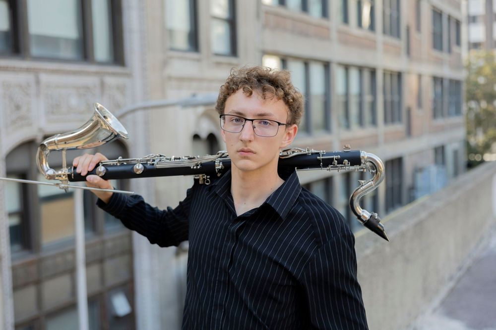 stoney creek senior in high school musician holding a bass clarinet on his shoulder outdoors in an urban setting.