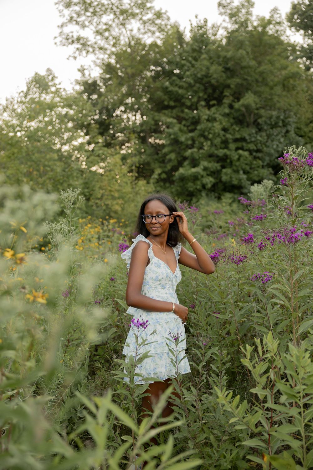a teenage girl posing for senior photos in a field of wildflowers in July in Birmingham michigan