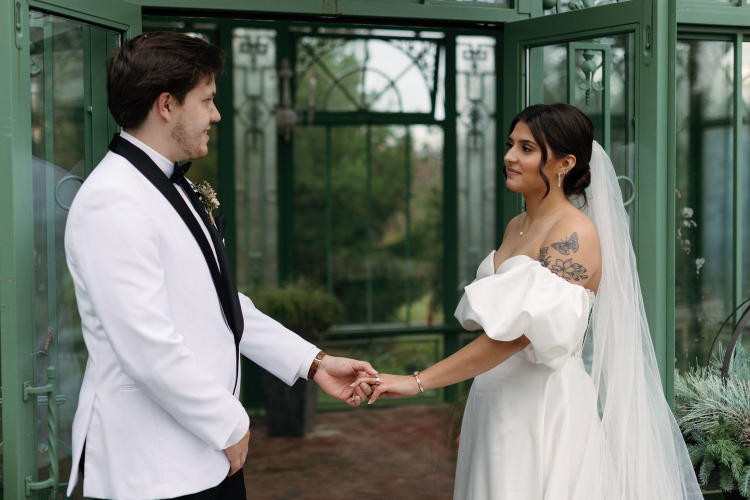 A couple shares an intimate moment in a greenhouse setting.