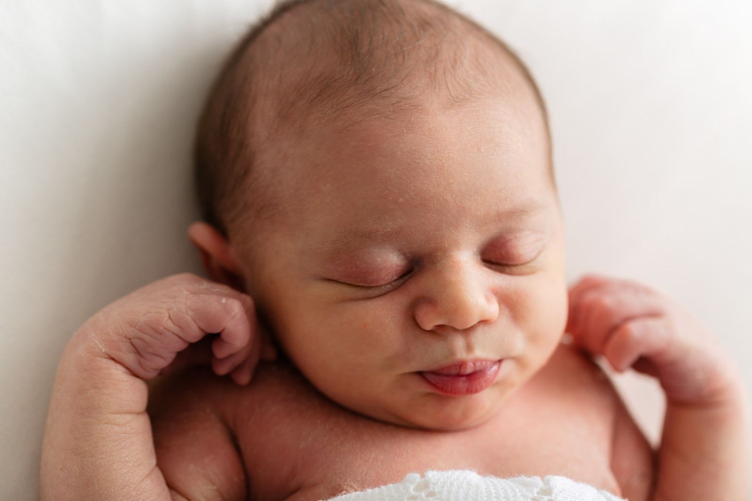 Peaceful sleeping newborn baby with soft skin and closed eyes rests during professional photo session.