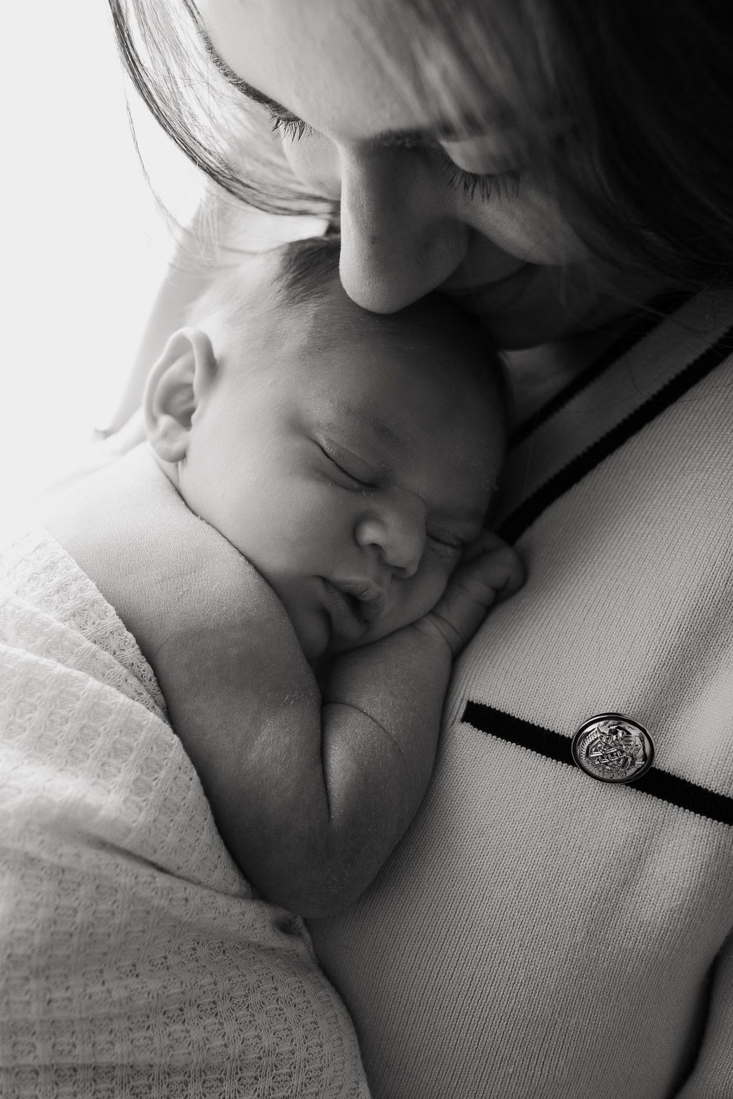 A tender black and white photograph shows a sleeping baby nestled against someone in peaceful repose.