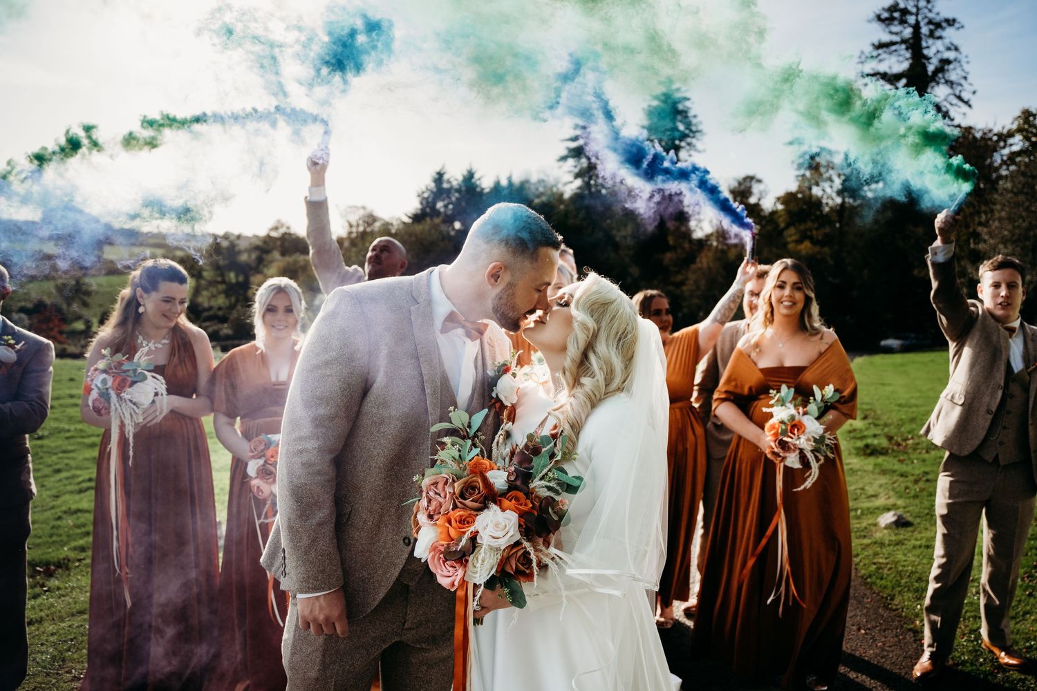 Wedding celebration with colorful smoke bombs creating a vibrant outdoor atmosphere.