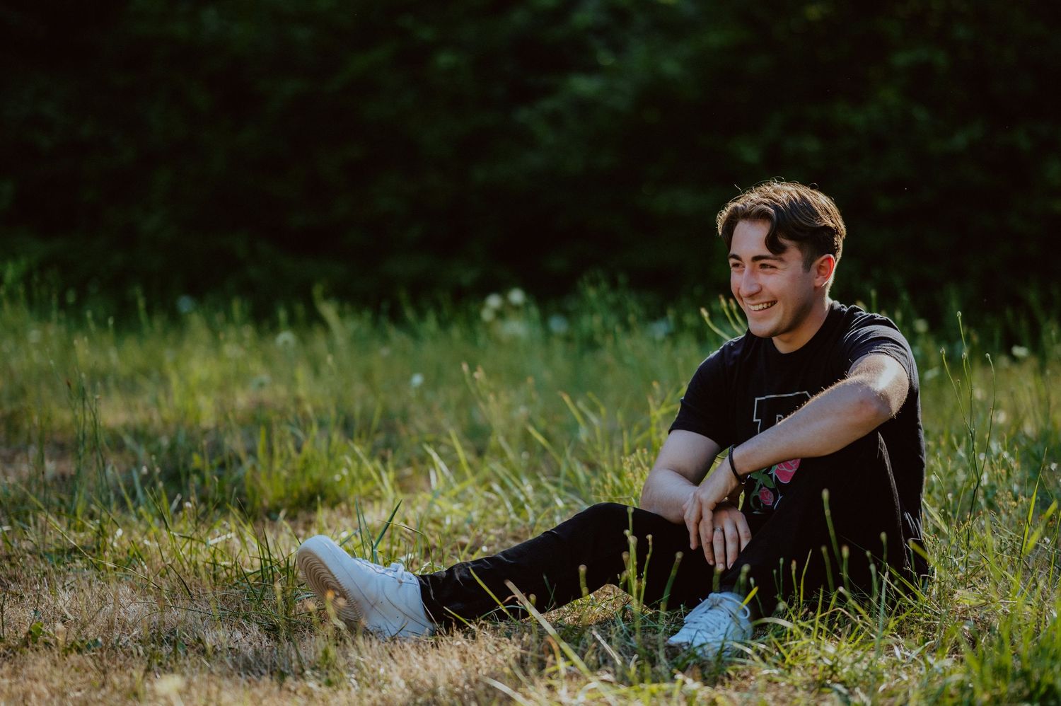 Person sitting casually in a grassy field during golden hour.