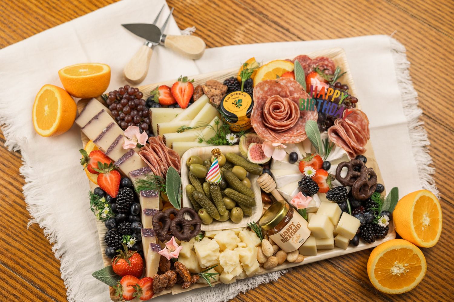 Beautifully arranged charcuterie board with meats, cheeses, fruits and rose-shaped garnish.