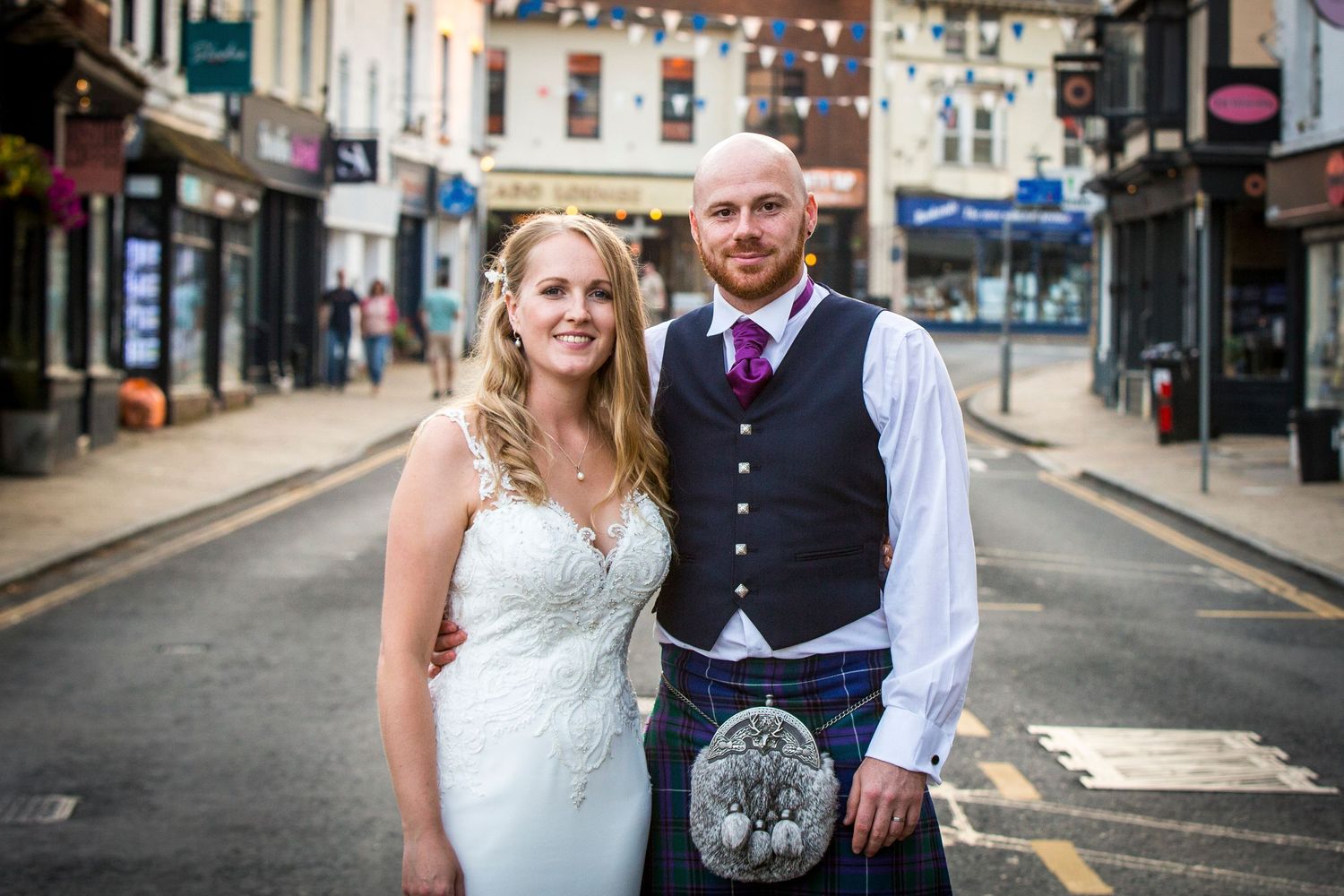 Newlyweds walking together through city streets on their wedding day.