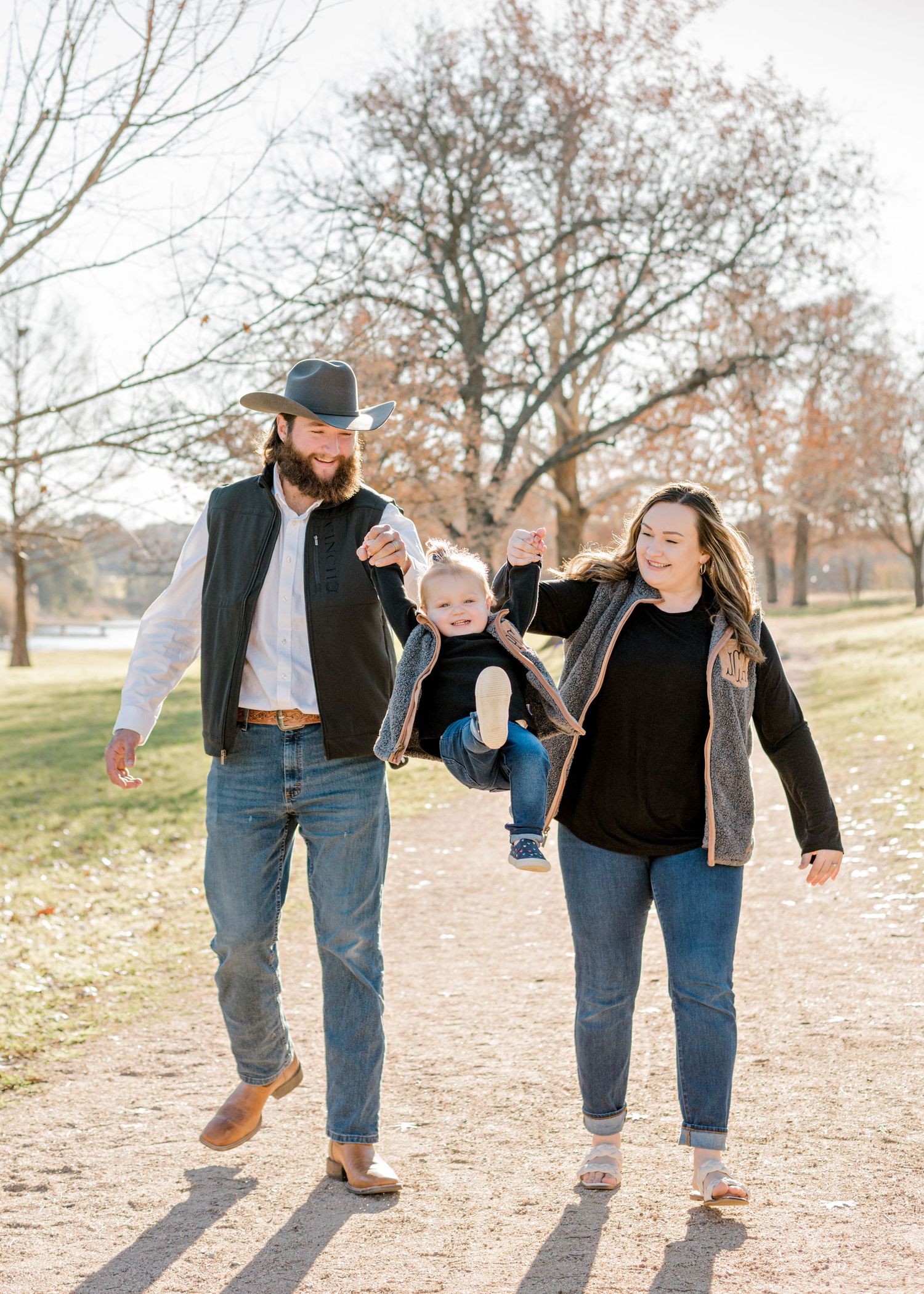 parents swinging their daughter in the air as they all walk together in Georgetown, TX.