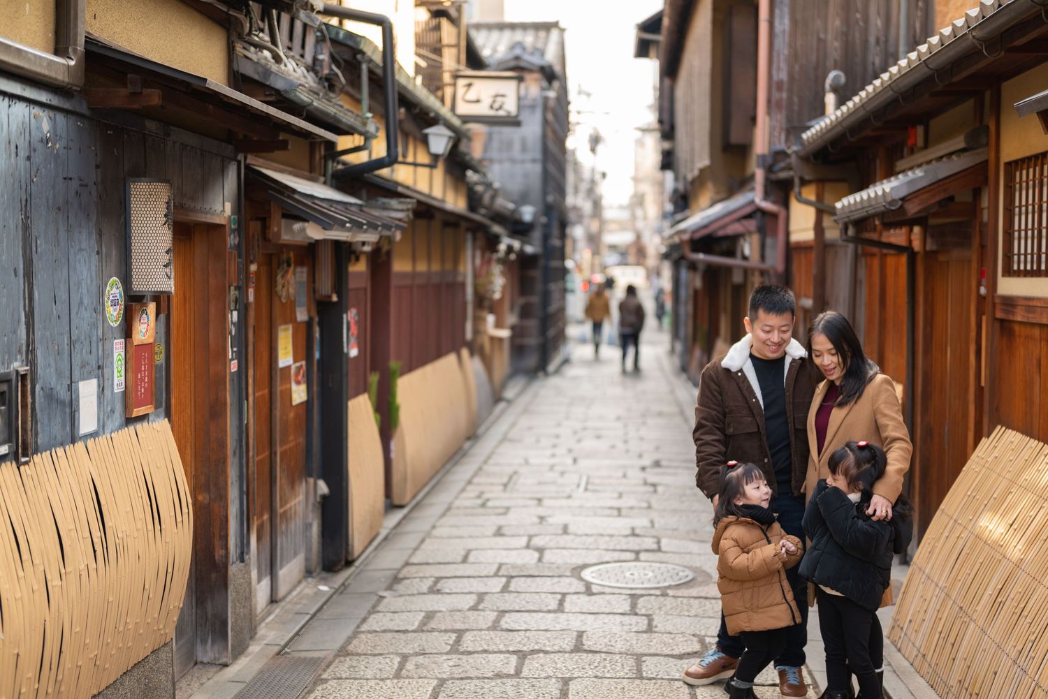 Family strolling down a traditional cobblestone alley in Kyoto's historic Gion district.