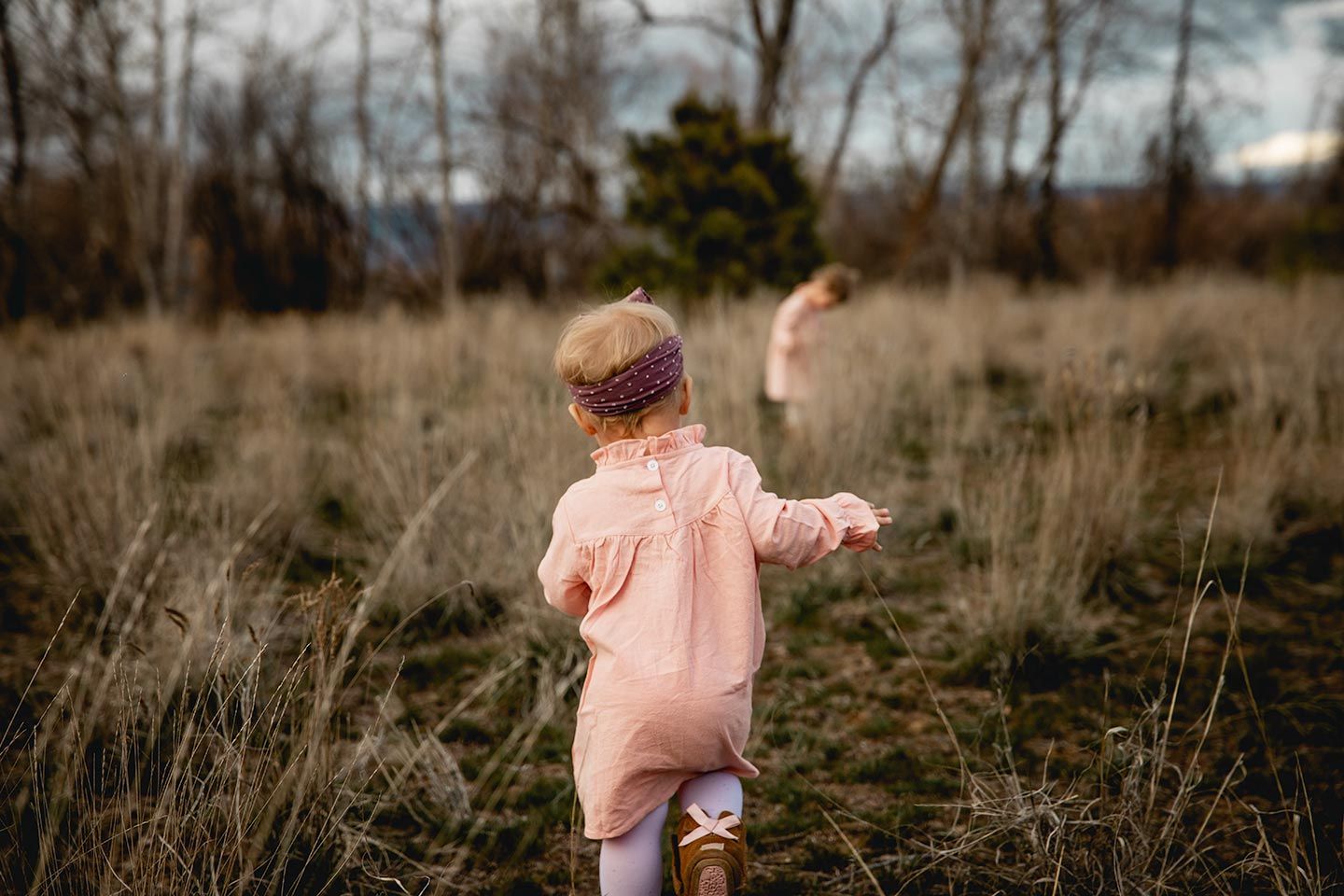 one year old wearing a dress and walking in a grassy field