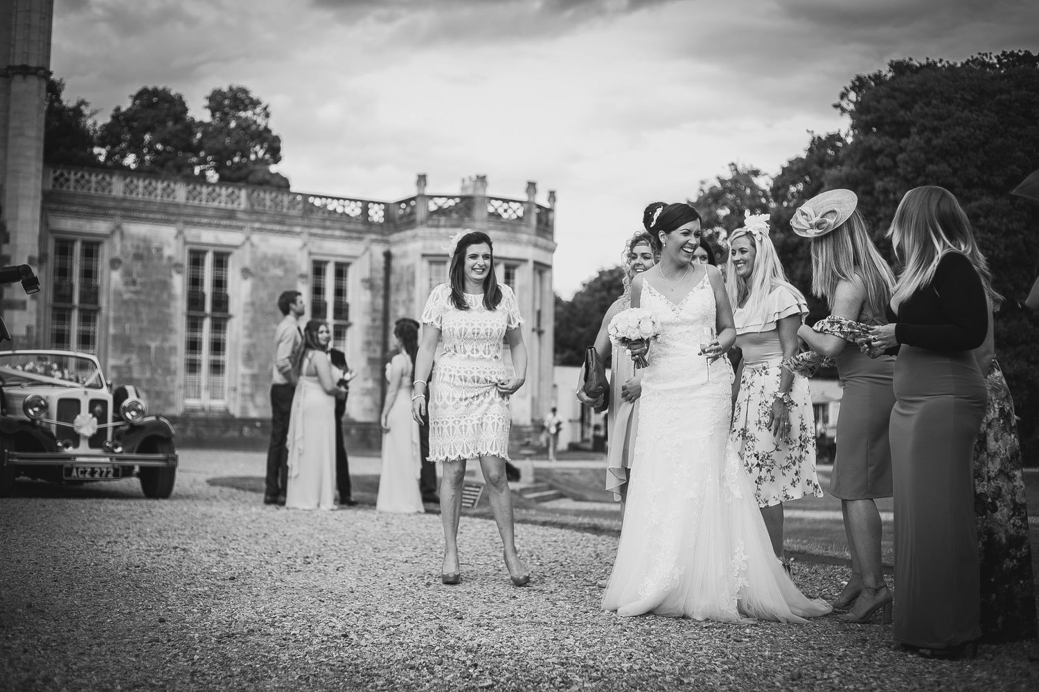 A bride laughs surrounded by her bridal party after getting married at Highcliffe Castle in Dorset