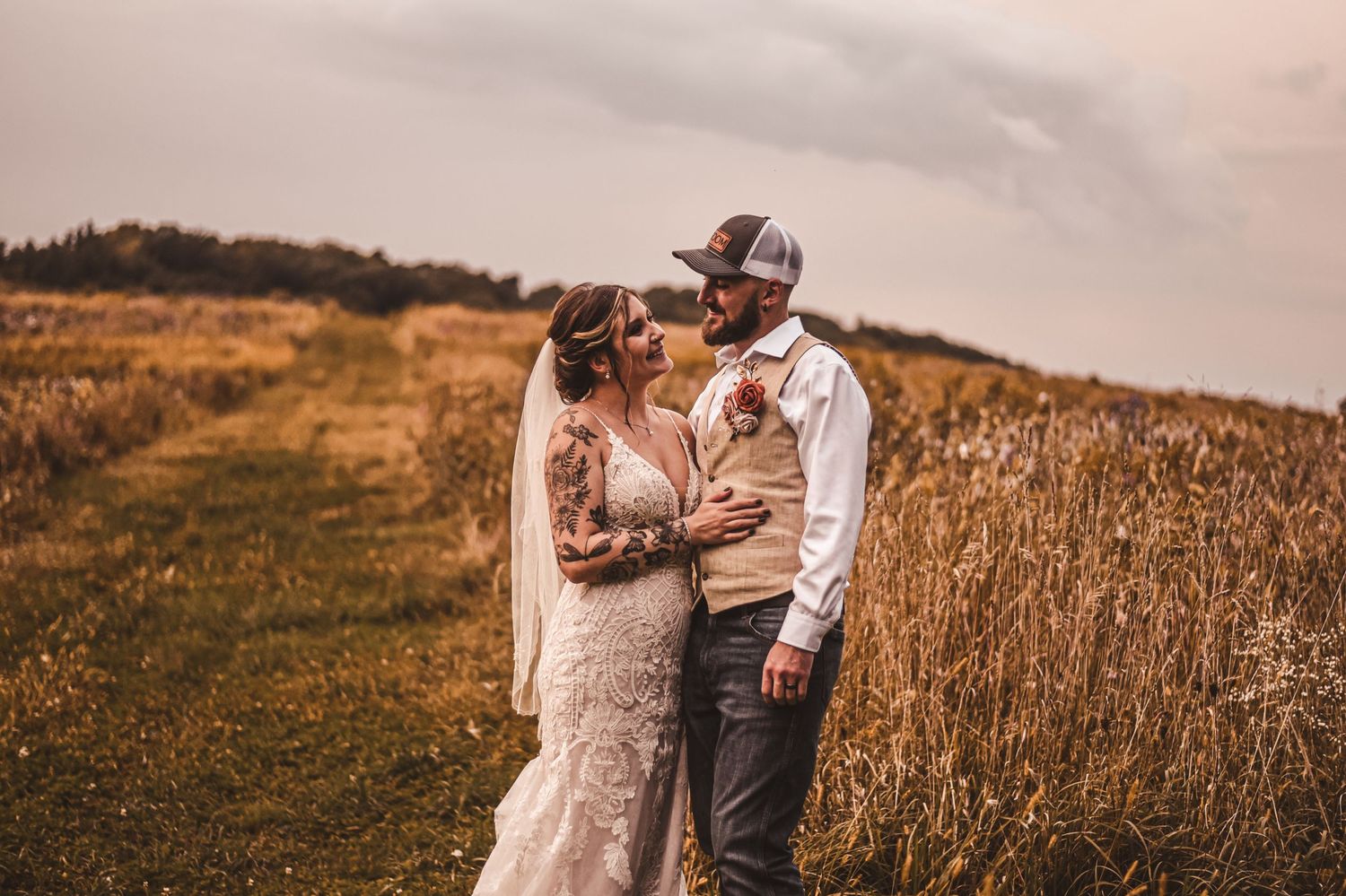 Romantic couple embraces in a golden wheat field during sunset.