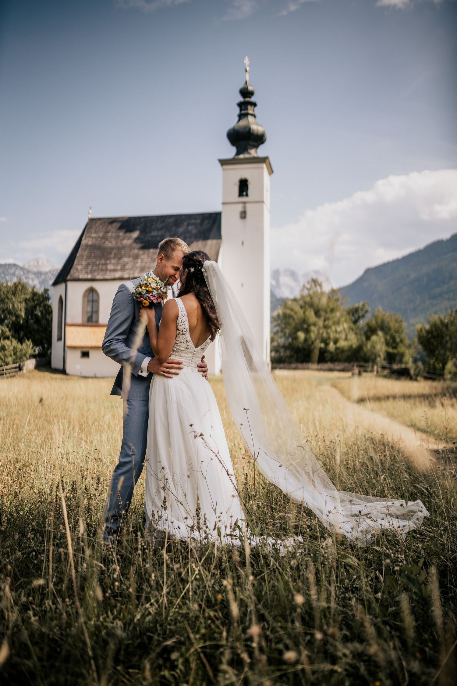 Brautpaar auf Sommerwiese vor Kirche in Torren