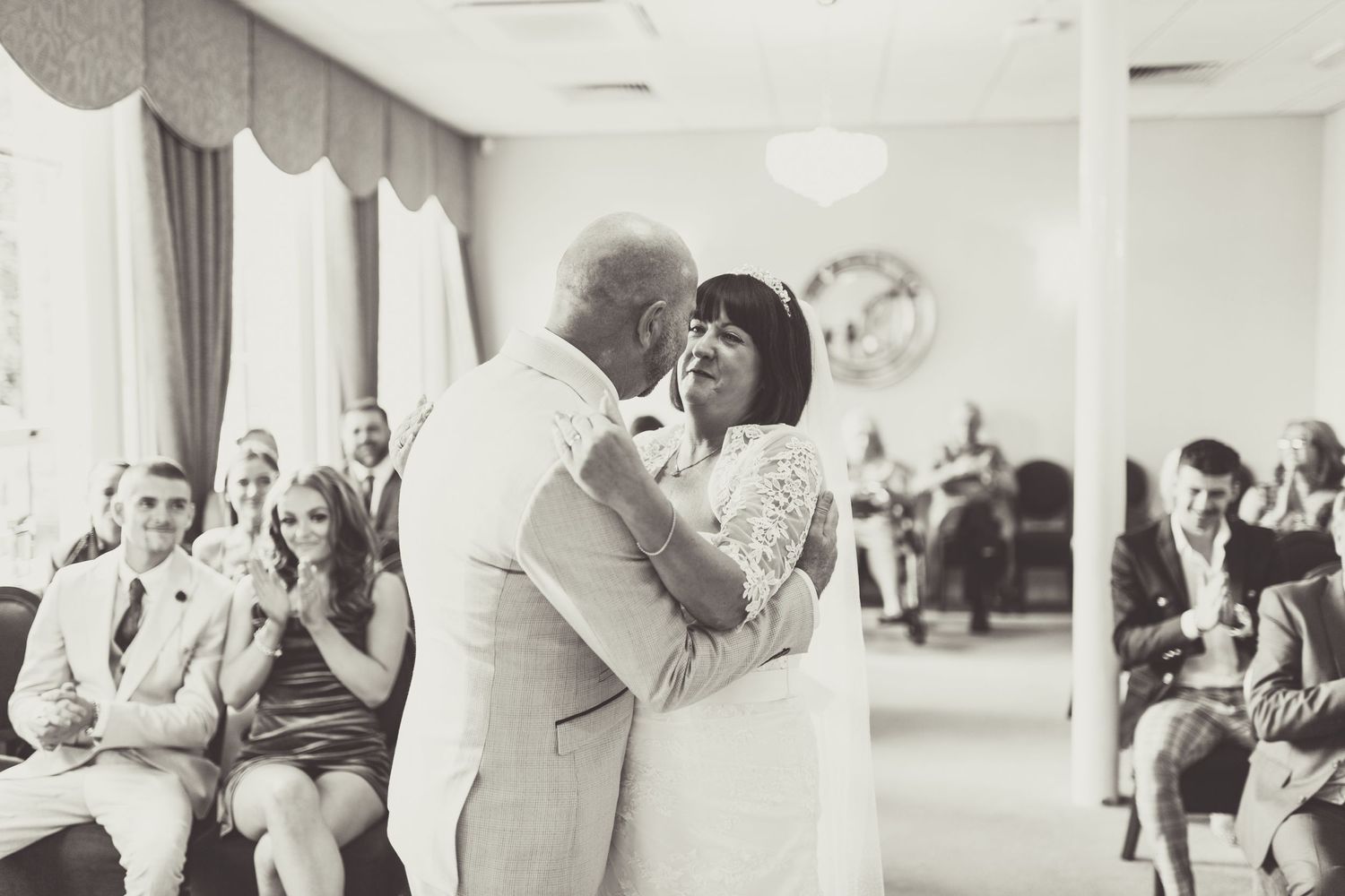 Wedding guests watch as a couple shares their first dance in a reception hall.