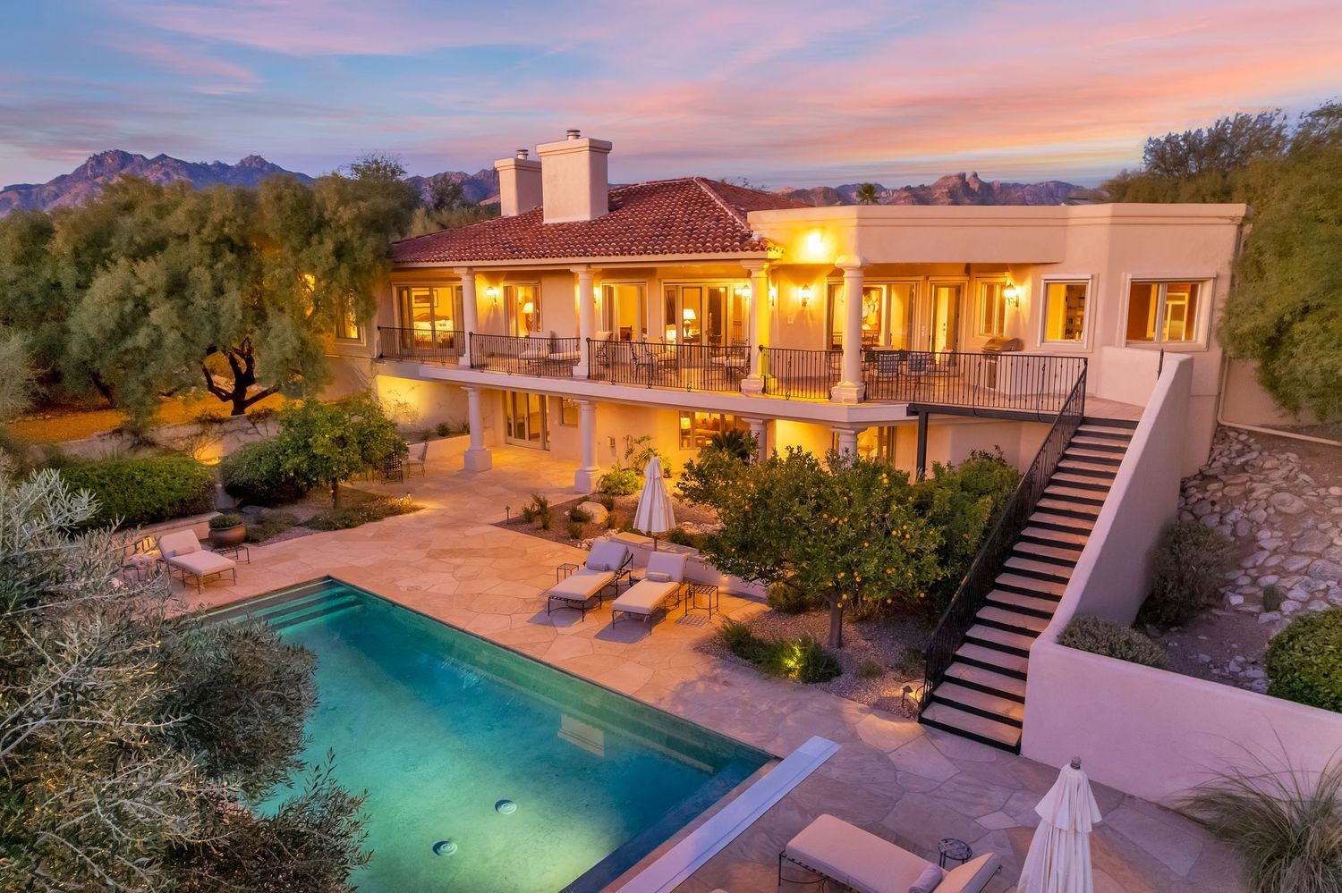 Modern desert estate with illuminated pool and patio during golden hour.