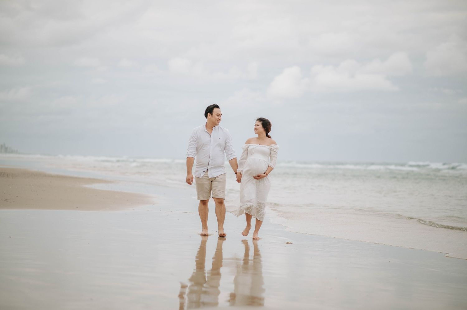 Couple walking together on a serene beach during sunset.