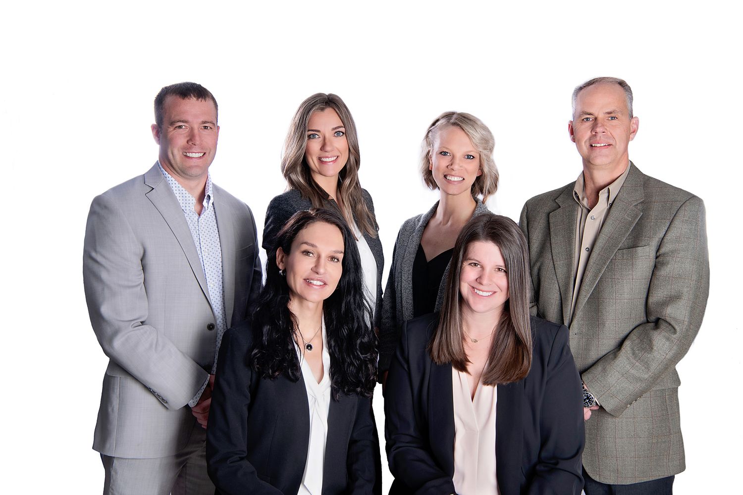 Professional group photo of business team in suits against white background.