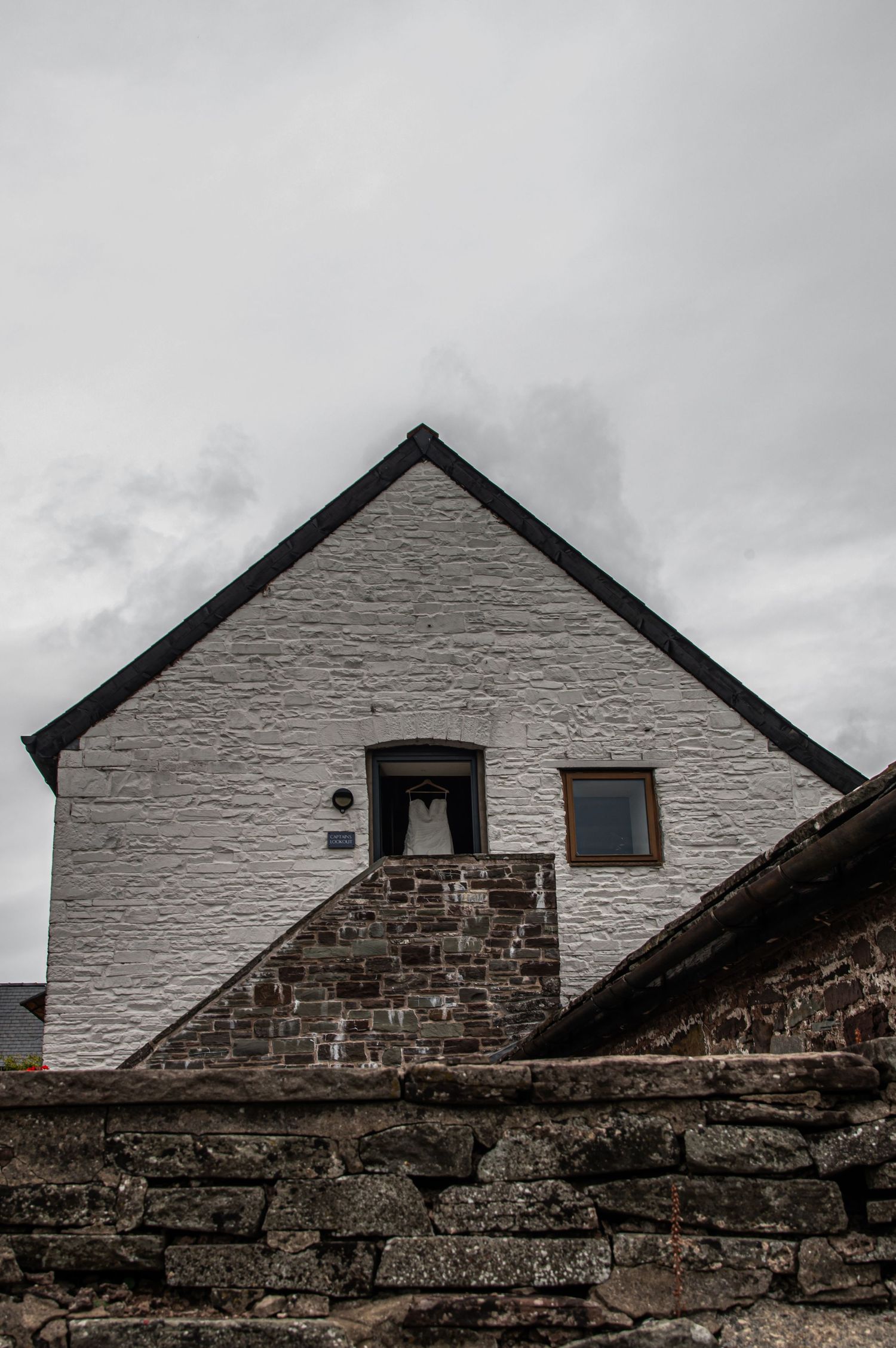 White-painted stone buildings with dark roofs against cloudy sky.