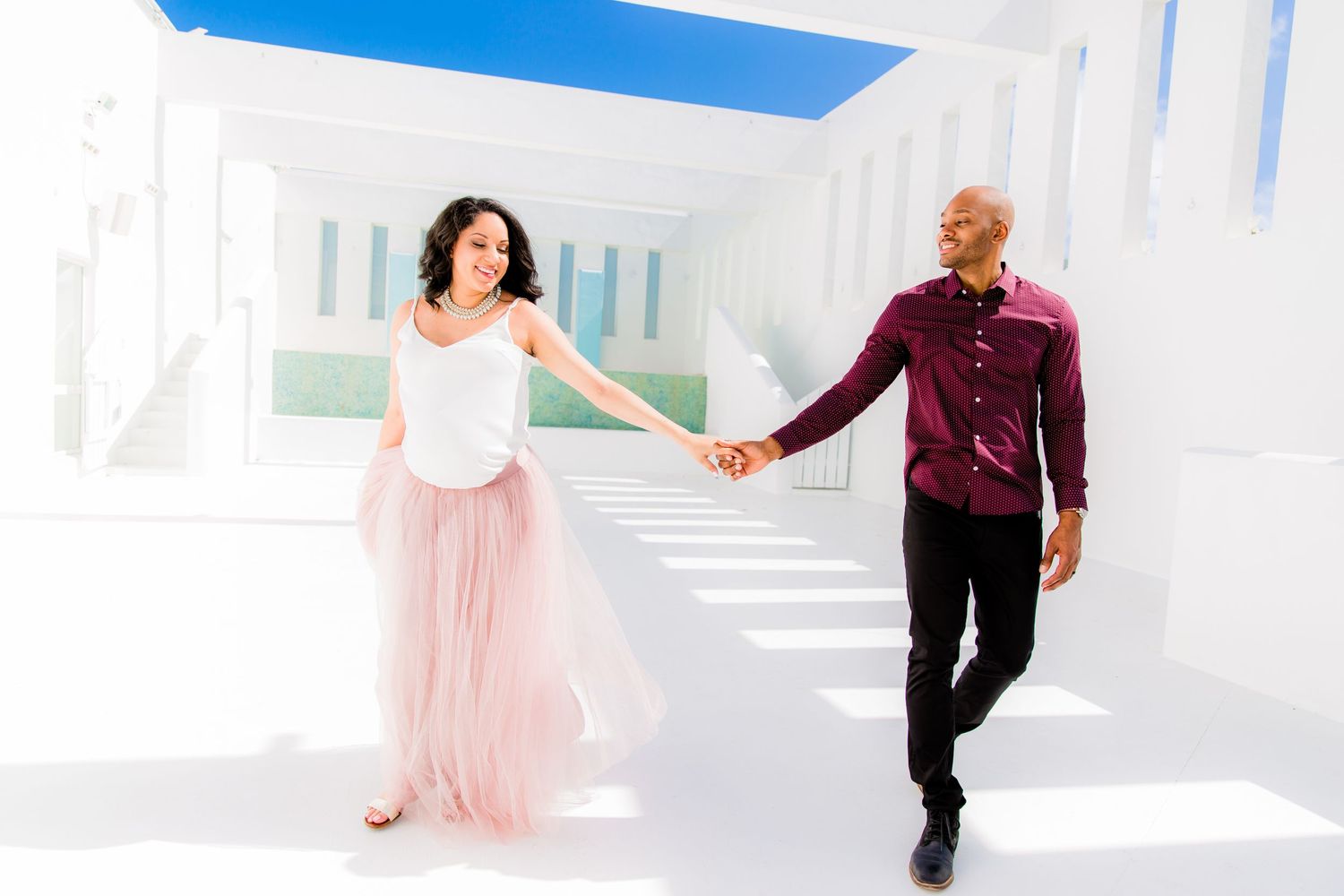 Romantic couple poses in an elegant white hallway with modern architecture.