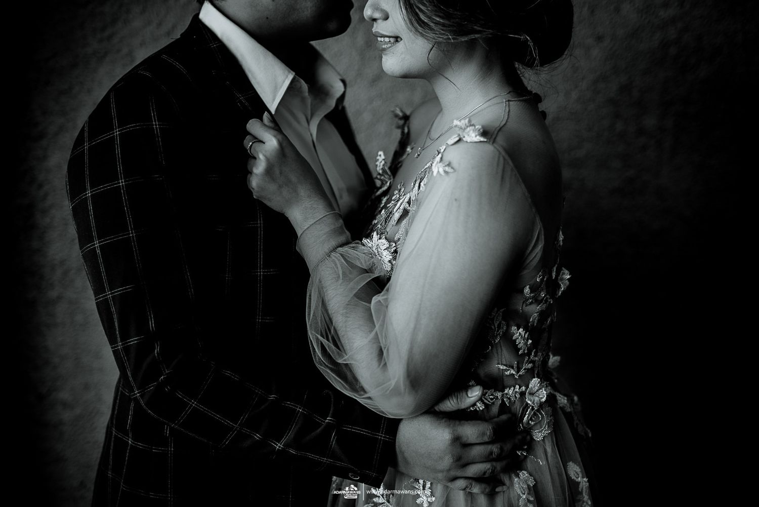 Intimate black and white portrait of a couple in formal attire embracing.