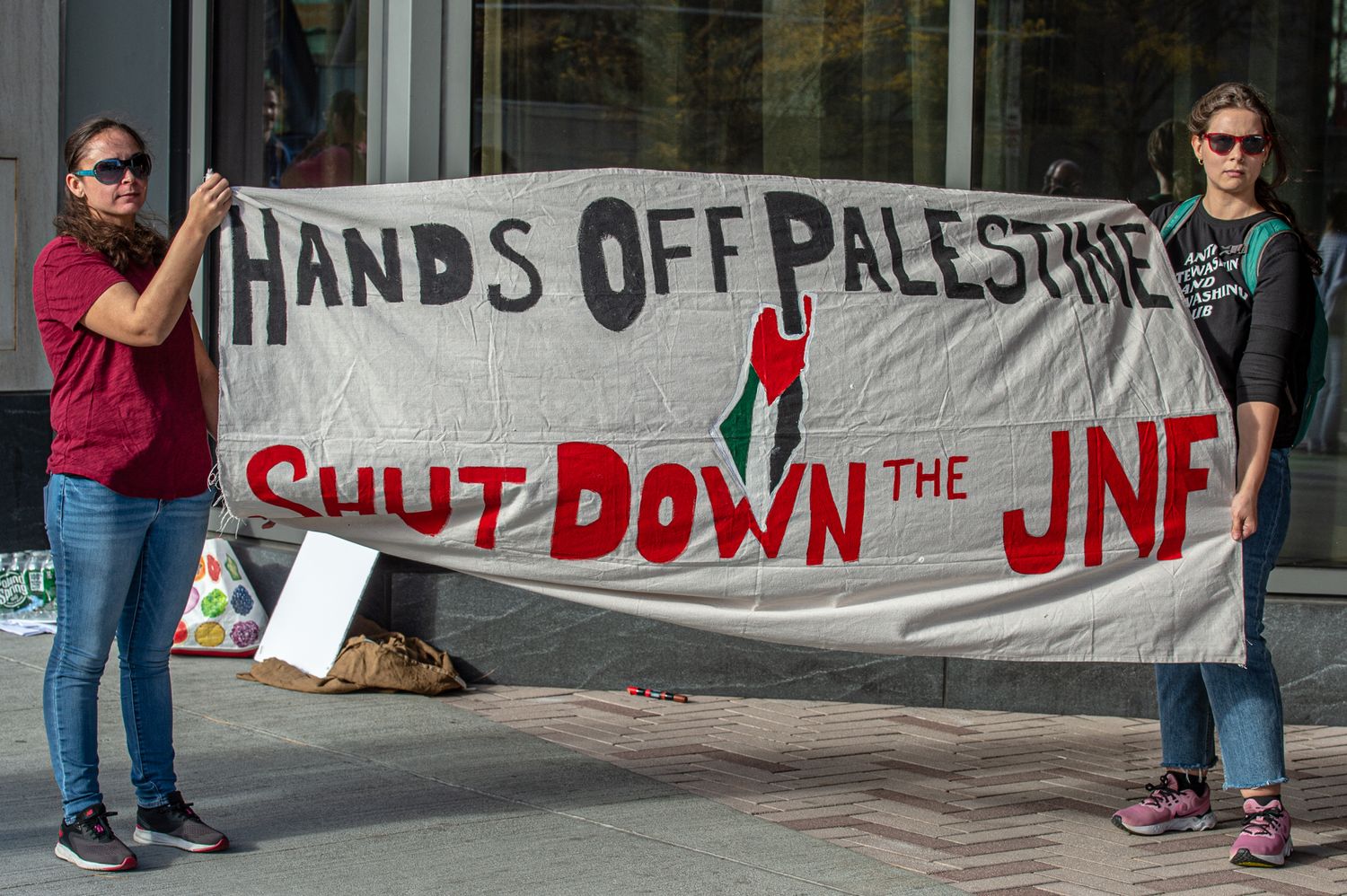 Protesters hold banner that reads Hands off Palestine. Shut down the JNF at Omni Hotel Boston Seaport