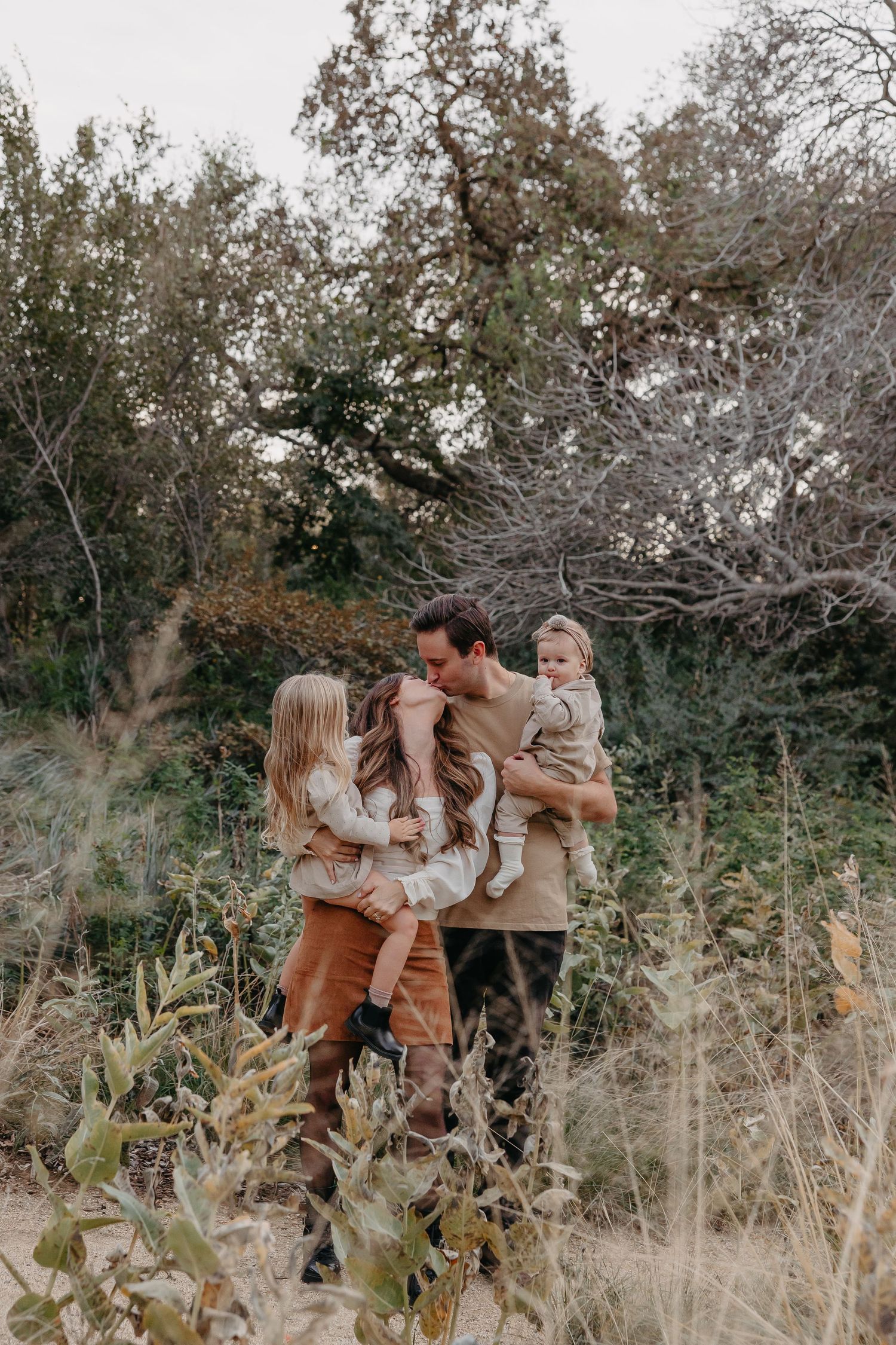 Family shares tender moment together in rustic fall field setting.