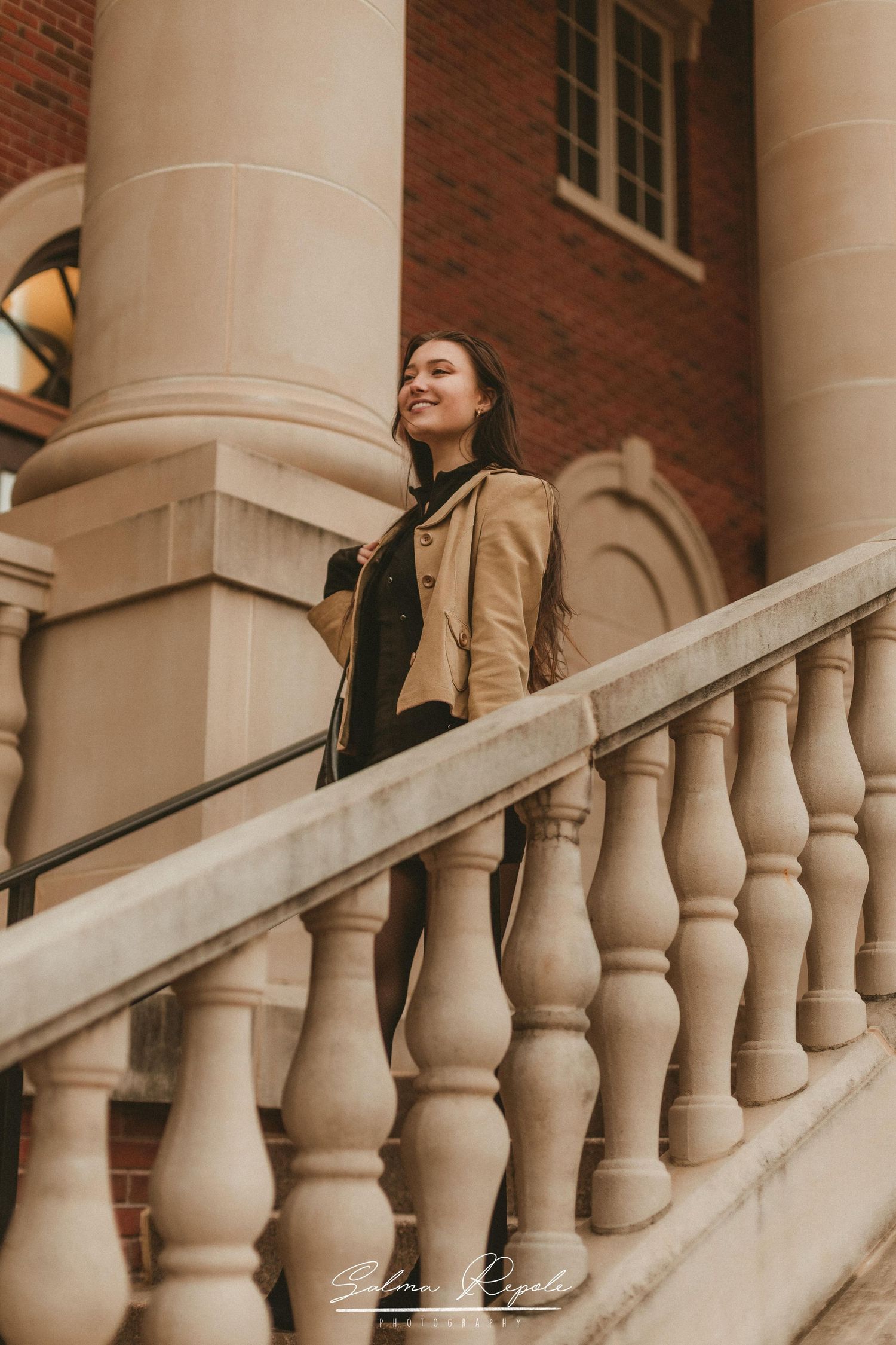 Architectural portrait on stone stairs with classic columns and brick details.