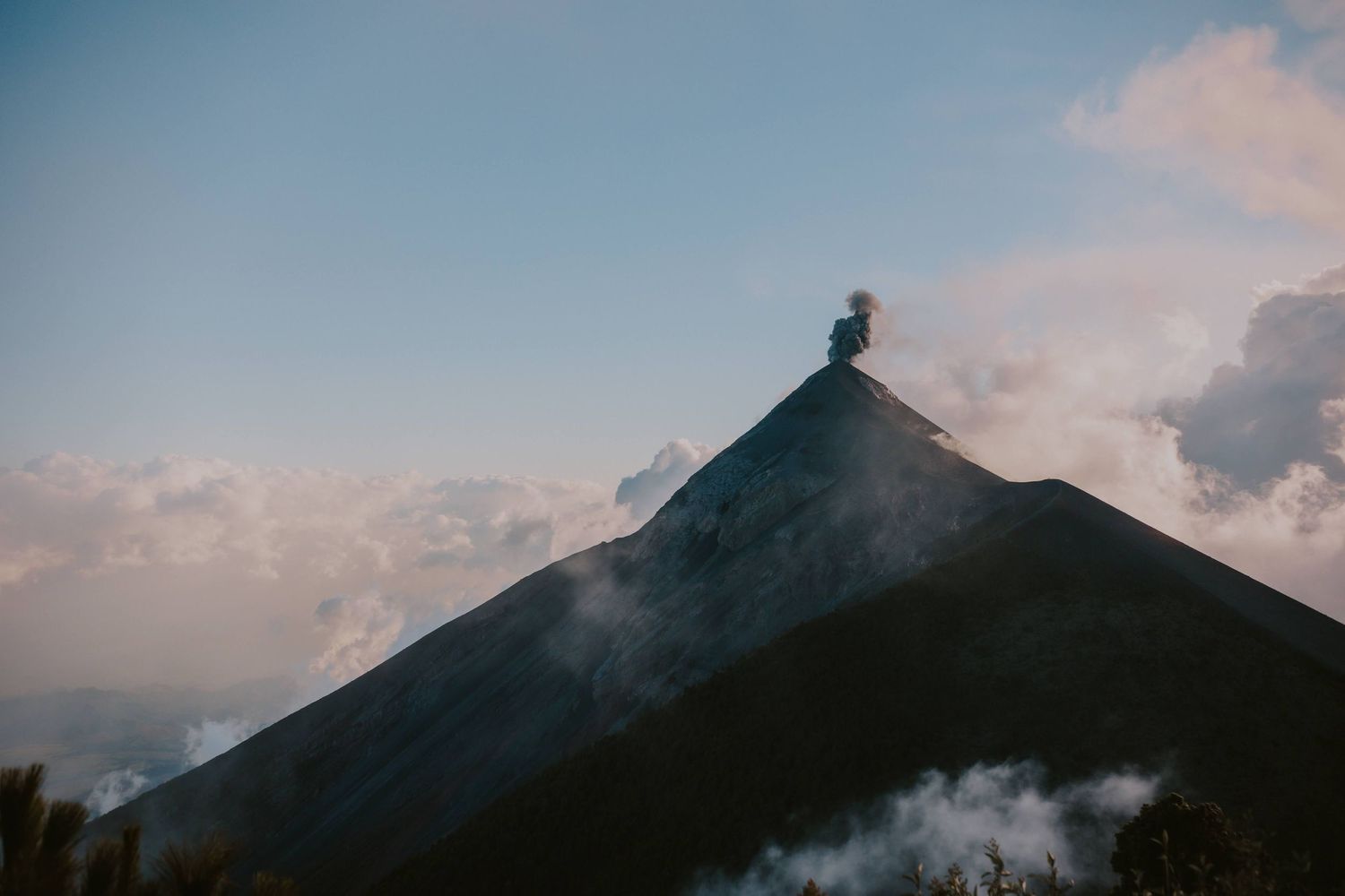 Silhouette of a mountain peak against sunset sky with clouds creating dramatic atmosphere.