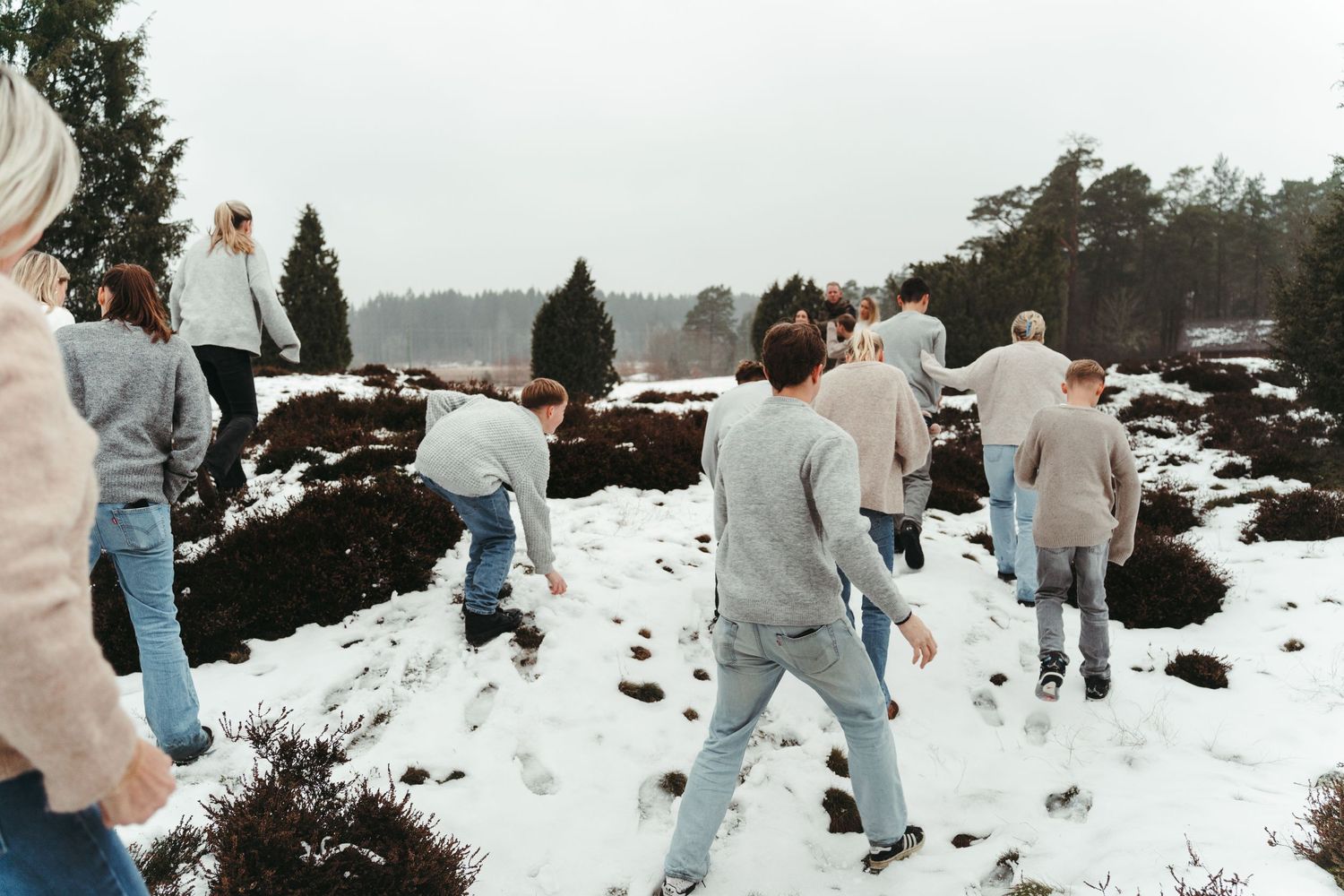 A group of people enjoying a snowy winter day outdoors among rocks and evergreen trees.
