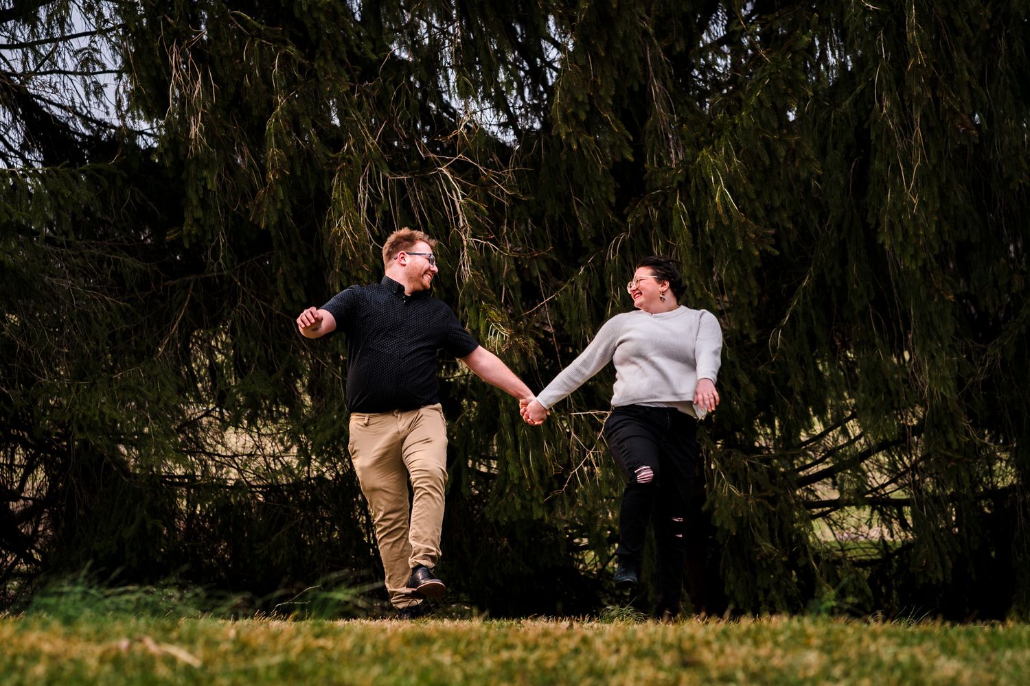 Playful outdoor photoshoot under a weeping willow tree in natural lighting.