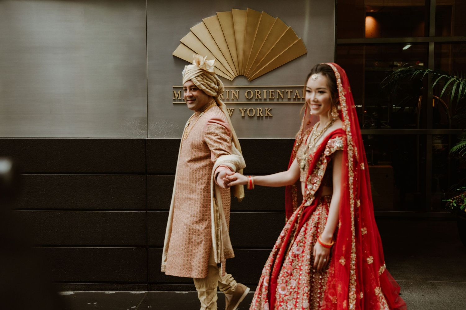 Traditional Indian wedding attire with ornate fan detail and red bridal lehenga.