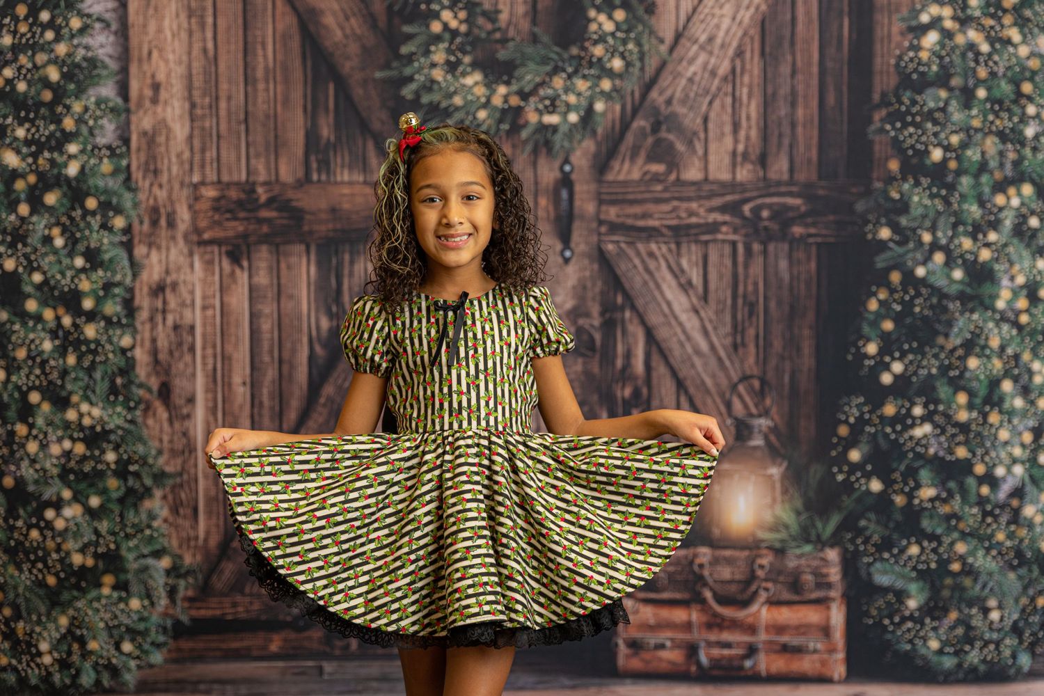 Rustic barn door photography backdrop with greenery and decorative lighting.
