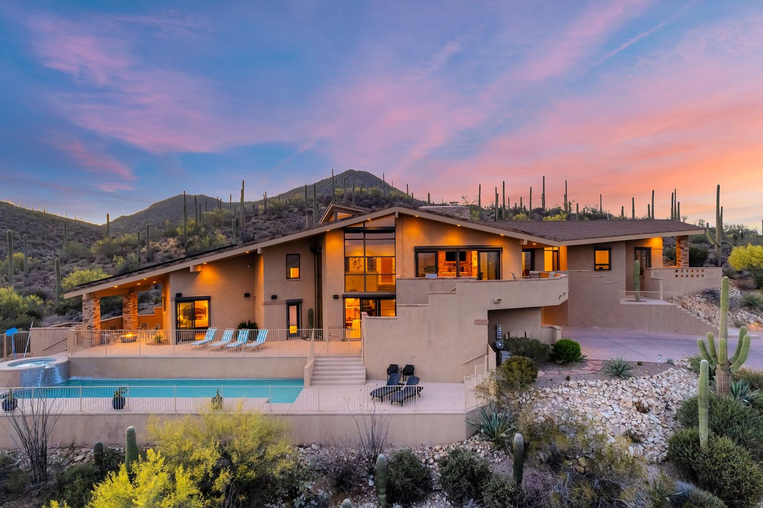 Luxury desert home with pool illuminated at sunset against mountain backdrop.