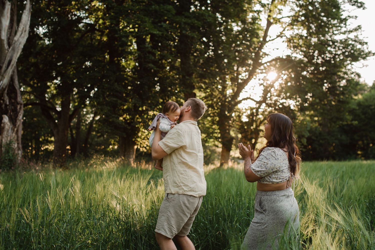 Couple dancing and playing together in a sunlit meadow at golden hour.