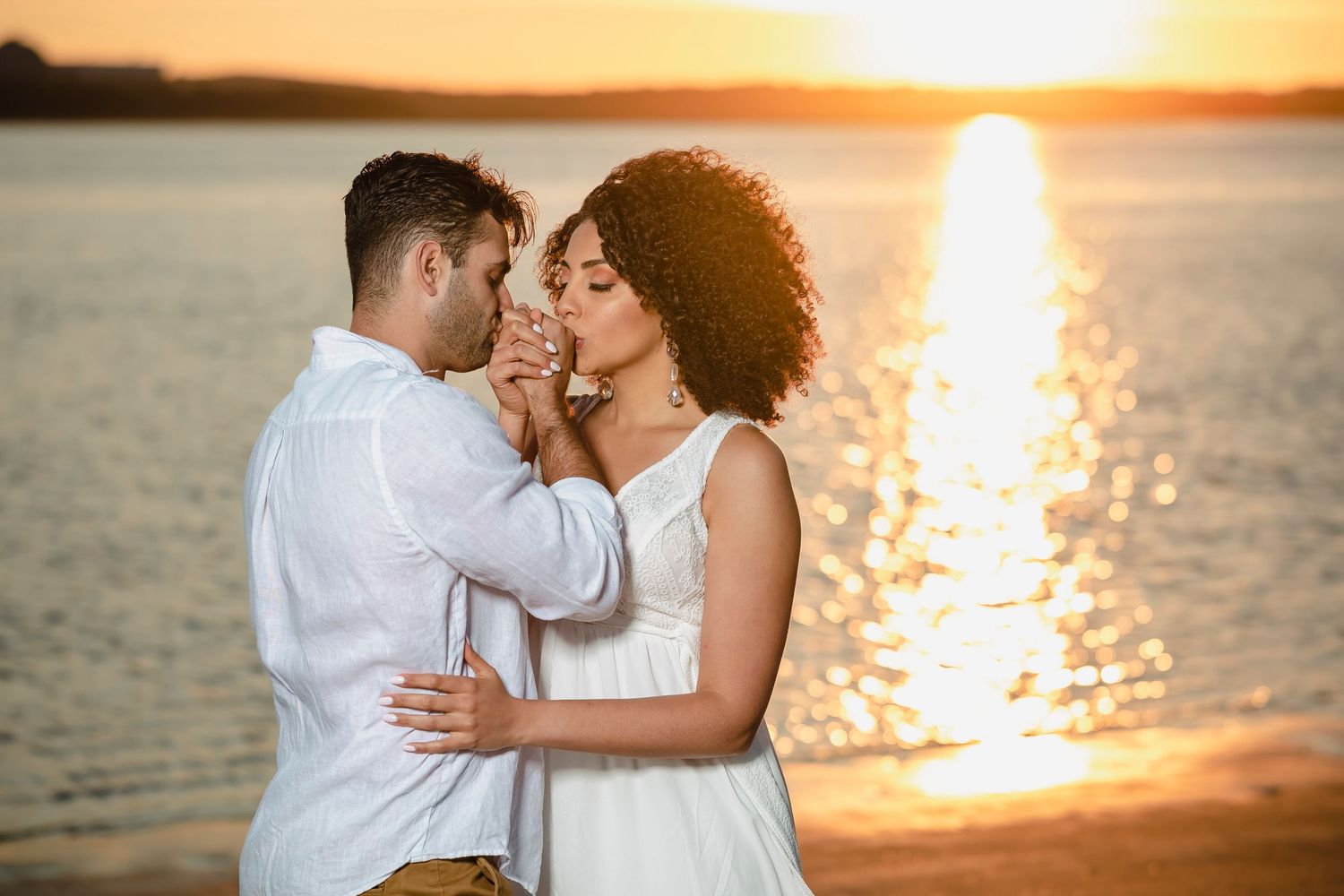 Romantic sunset beach portrait with golden light reflecting on the water.