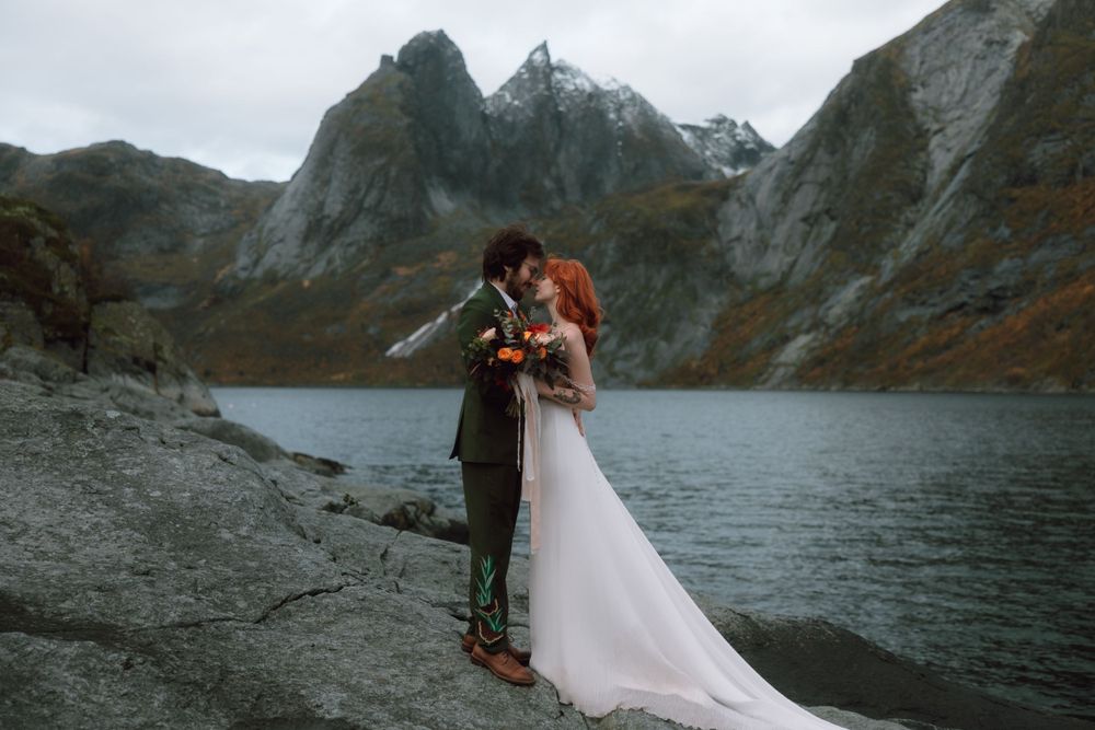 Dramatic mountain lake elopement ceremony with fog and rugged peaks in the background.
