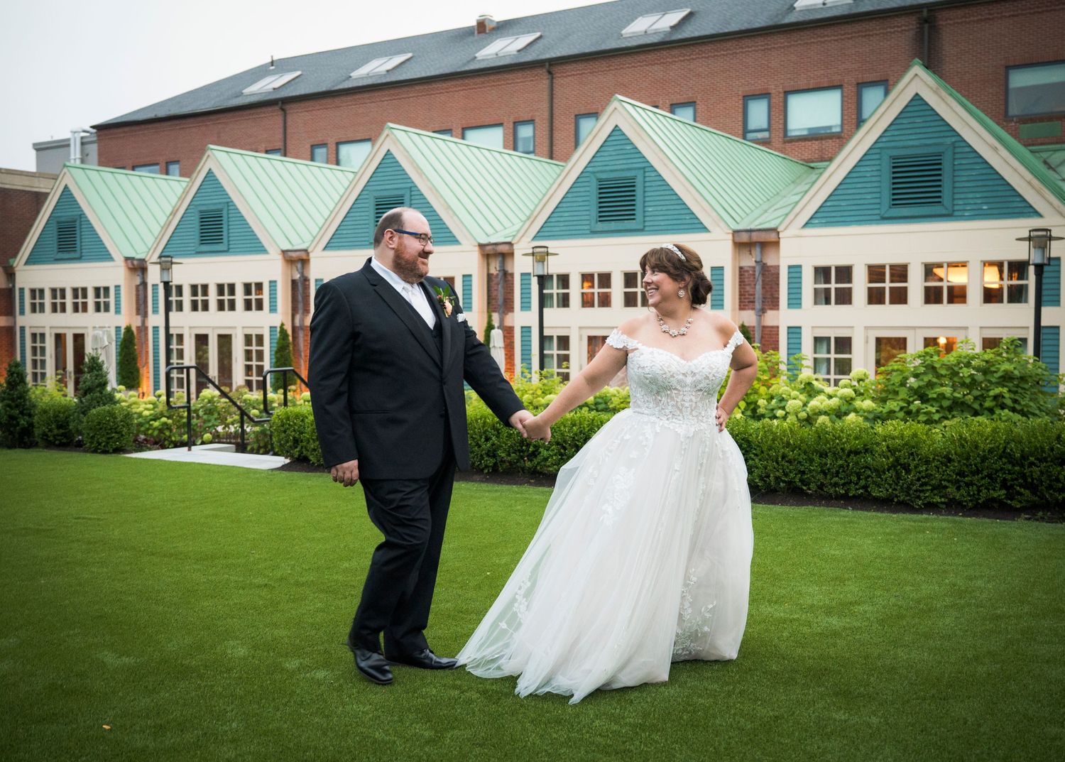 A joyful moment on green lawn in front of mint-colored beach house style buildings.