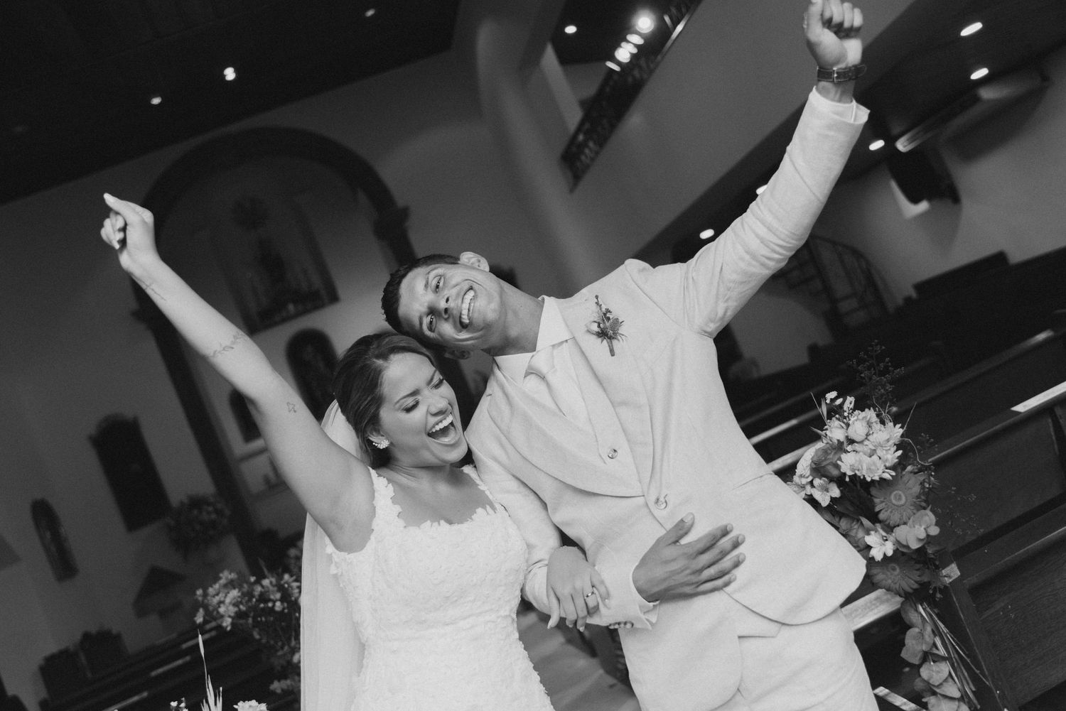 A joyful couple raises their arms in celebration during their wedding dance.